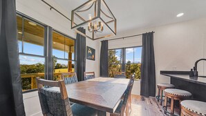 Ein moderner Essbereich mit großem Tisch, Stühlen und Blick ins Freie.