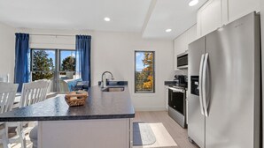 Uma cozinha moderna com ilha central, eletrodomésticos de aço inoxidável e janelas amplas.