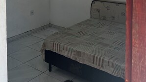 Ein schlichter, einfach eingerichteter Raum mit einem Bett, einem Wand-Fernseher und einem Fliesenboden.