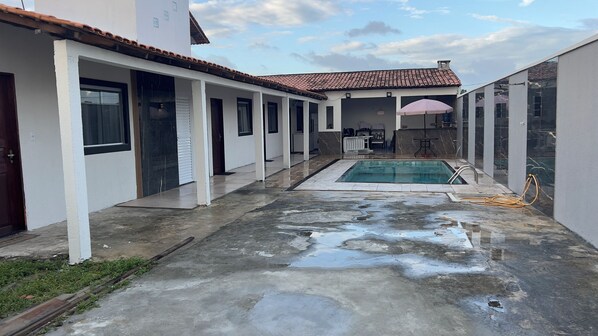 A residential property with a swimming pool, a covered patio area, and a garage.