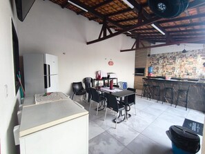 A compact kitchen with a dining area, a refrigerator, a microwave, and a bar area with stools.