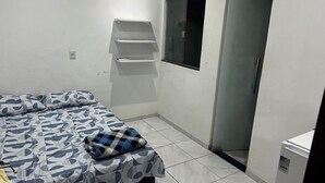 Ein Schlafzimmer mit einem Bett, einem Fenster, einer Tür und einem kleinen weißen Schrank.