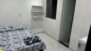 Ein Schlafzimmer mit einem Bett, einem Fenster, einer Tür und einem kleinen weißen Schrank.