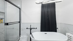 Een moderne badkamer met een douchecabine van glas, een vrijstaand bad en een zwart douchegordijn.