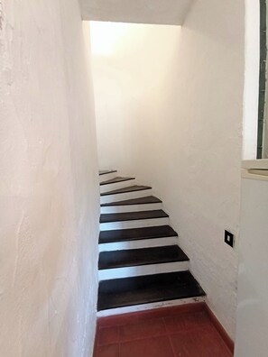 A narrow staircase with white walls and black steps leading to a lower level. - Villa Alba Costa Rei, 5 minutes from the beach (Costa Rei)