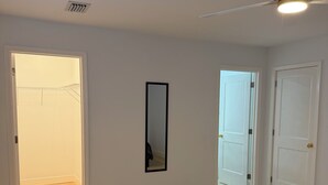 A room with a ceiling fan, a door, a mirror, and a hallway leading to another room. - Charming 2BR/2BA Getaway – Feels Like Home (Tampa)
