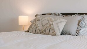A neatly made bed with patterned pillows, a bedside lamp, and a framed picture on the wall.