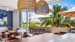 Uma sala de estar moderna com uma janela ampla, um ventilador de teto e um espaço de refeições com mesa e cadeiras.