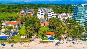 A resort with multiple buildings, a beach, and palm trees. - Spacious Penthouse with ocean views, pool & balcony (Nuevo Vallarta)