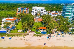 A resort with multiple buildings, a beach, and palm trees. - Spacious Penthouse with ocean views, pool & balcony (Nuevo Vallarta)