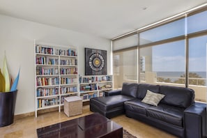 Uma sala de estar moderna com um sofá de couro, uma estante e uma janela grande com vista.