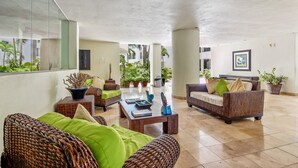 Un espacio interior amplio con muebles de mimbre, una mesa de centro y plantas en macetas.
