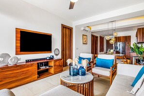 A modern living room with a large TV, wooden furniture, and a dining area. - DToscana 305 2BR/2BA Nuevo Vallarta condo near ocean, pool & gym (Nuevo Vallarta)