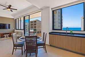 Eine moderne Küche mit einem großen Fenster, einem Essbereich mit Stühlen und einem Deckenventilator.