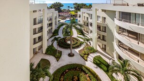 A hotel with a central courtyard, multiple balconies, and a view of the ocean. - Luxurious Penthouse with a scenic terrace pool & modern kitchen (Nuevo Vallarta)
