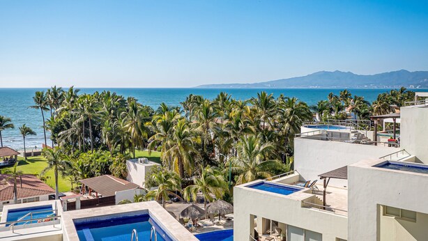 A resort with multiple swimming pools, a view of the ocean, and palm trees. - Luxurious Penthouse with a scenic terrace pool & modern kitchen (Nuevo Vallarta)