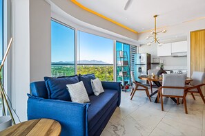 Un salon moderne comprenant un canapé, une table à manger, des chaises et de grandes fenêtres donnant sur une vue imprenable sur les montagnes.