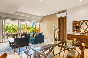 A modern living room with a glass coffee table, blue sofa, and wooden sideboard. - 2BR/2BA Nuevo Vallarta Condo | Pool, Gym & Balcony (Nuevo Vallarta)