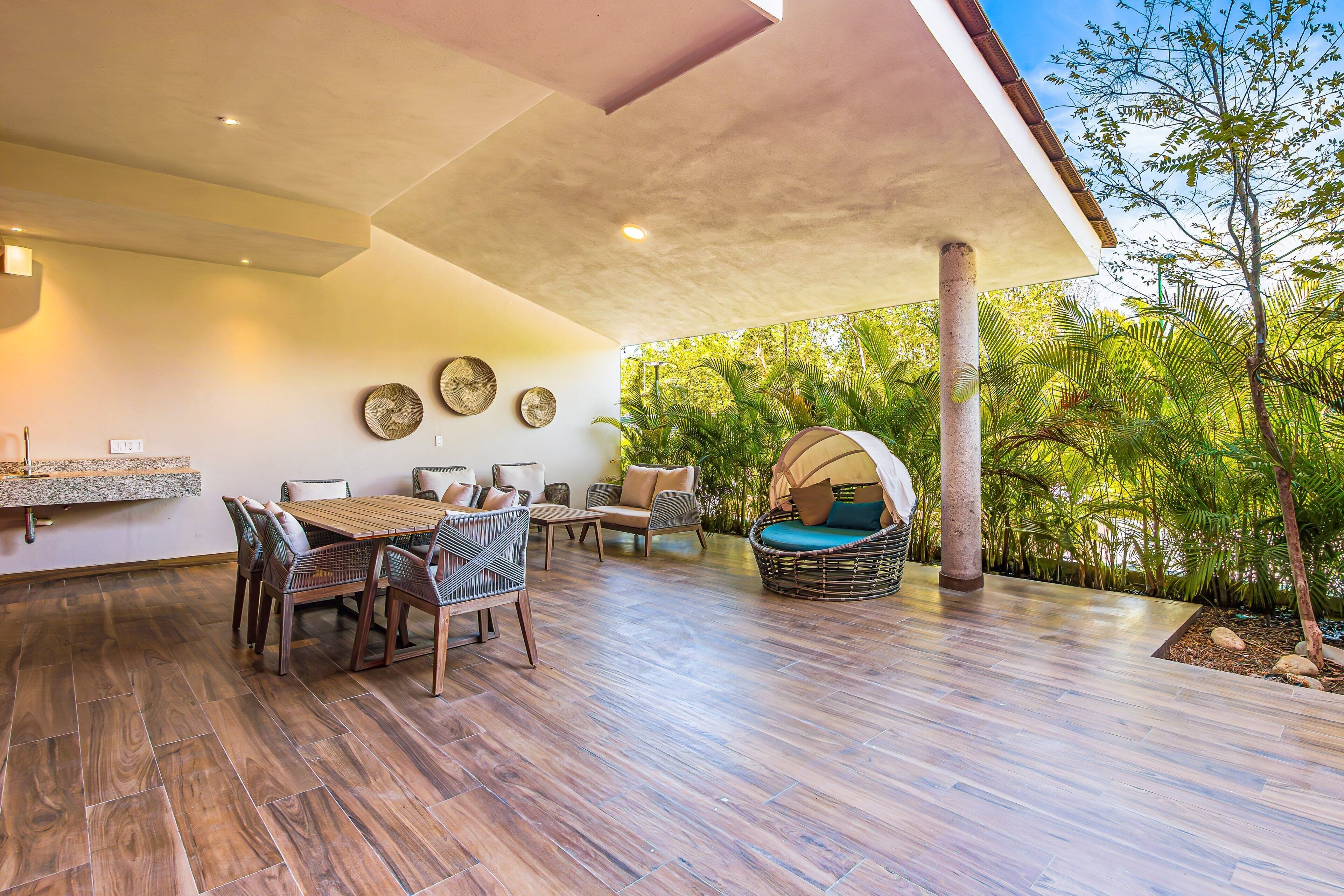 Un patio moderno al aire libre con comedor, asientos y vista a vegetación exuberante.