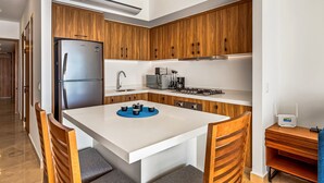 Une cuisine moderne avec des meubles en bois, un réfrigérateur en acier inoxydable, un four à micro-ondes et une cuisinière à gaz.