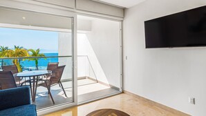 Un balcon avec vue sur l’océan, un téléviseur à écran plat fixé au mur et une table ronde en bois.
