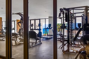 Ein Fitnessraum mit Trainingsgeräten, großen Fenstern und Blick ins Freie.