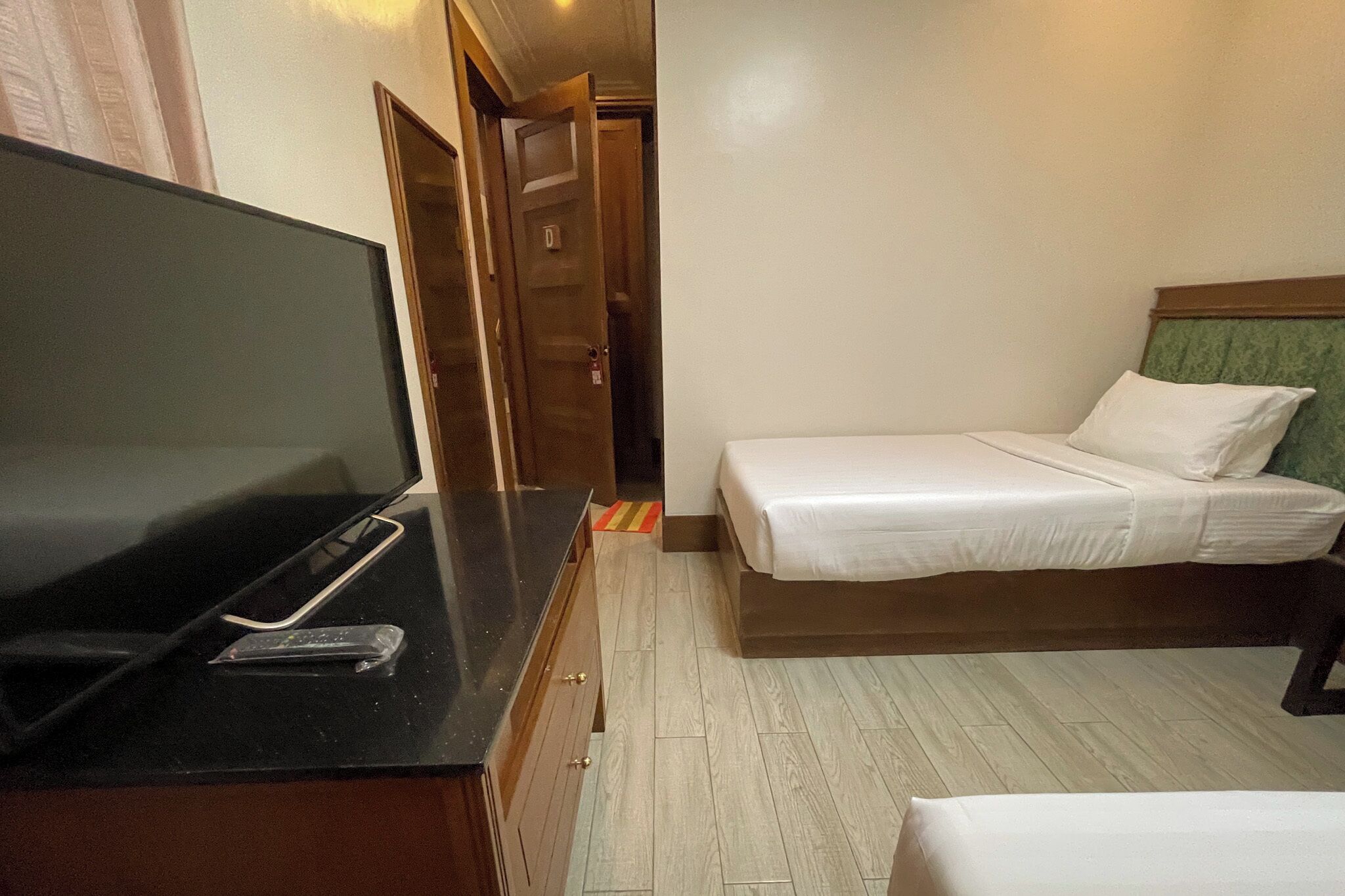 Una habitación de hotel con una cama, un televisor en un escritorio y una puerta que da a otra habitación.