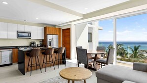 Uma cozinha moderna com área de bar, espaço de jantar com vista para o oceano e sala de estar com uma grande janela.