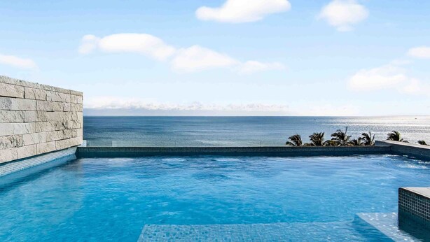 Piscina com vista para o oceano e uma parede de pedra.