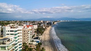 Paisagem urbana costeira com praia, edifícios e céu claro.