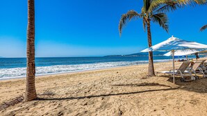 Une plage bordée de palmiers, un ciel bleu azur et une mer calme.