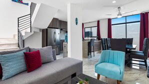 A modern living room with a grey sofa, a blue armchair, and a black coffee table. - 3BR/2.5BA Porto Residencial in Nuevo Nayarit, near ocean, pool, patio, WiFi (Nuevo Vallarta)