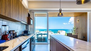 Een moderne keuken met uitzicht op zee, een balkon en een eethoek.
