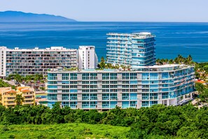 Ein mehrstöckiges Hotel mit gebogener Fassade, großen Fenstern und Meerblick.