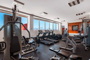 A gym with various exercise equipment, large windows, and a view of the mountains. - 2BR/2BA Nuevo Nayarit condo near ocean, pool, gym (Nuevo Vallarta)