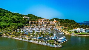 A marina with boats docked, surrounded by lush greenery and buildings with red roofs. - Coastal Couples Retreat | Plunge Pool + Hammocks (La Culebra)