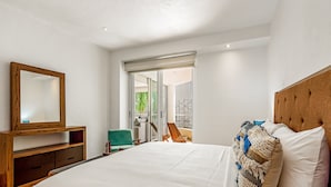 A bedroom with a large bed, a wooden dresser, a mirror, and a view of a balcony. - Luxury Beach Condo | Community Pool, Ocean Views, Walk to Beach (Nuevo Vallarta)