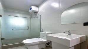 A bathroom with a glass shower enclosure, a toilet, and a sink. - Supreme Apartments (Ibadan)