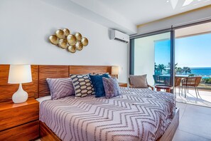 A bedroom with a bed, bedside table, lamp, decorative wall piece, and a balcony with a view. - Aria Ocean Condo, 1BR/1BA, Nuevo Vallarta—oceanfront pool, WiFi (Nuevo Vallarta)