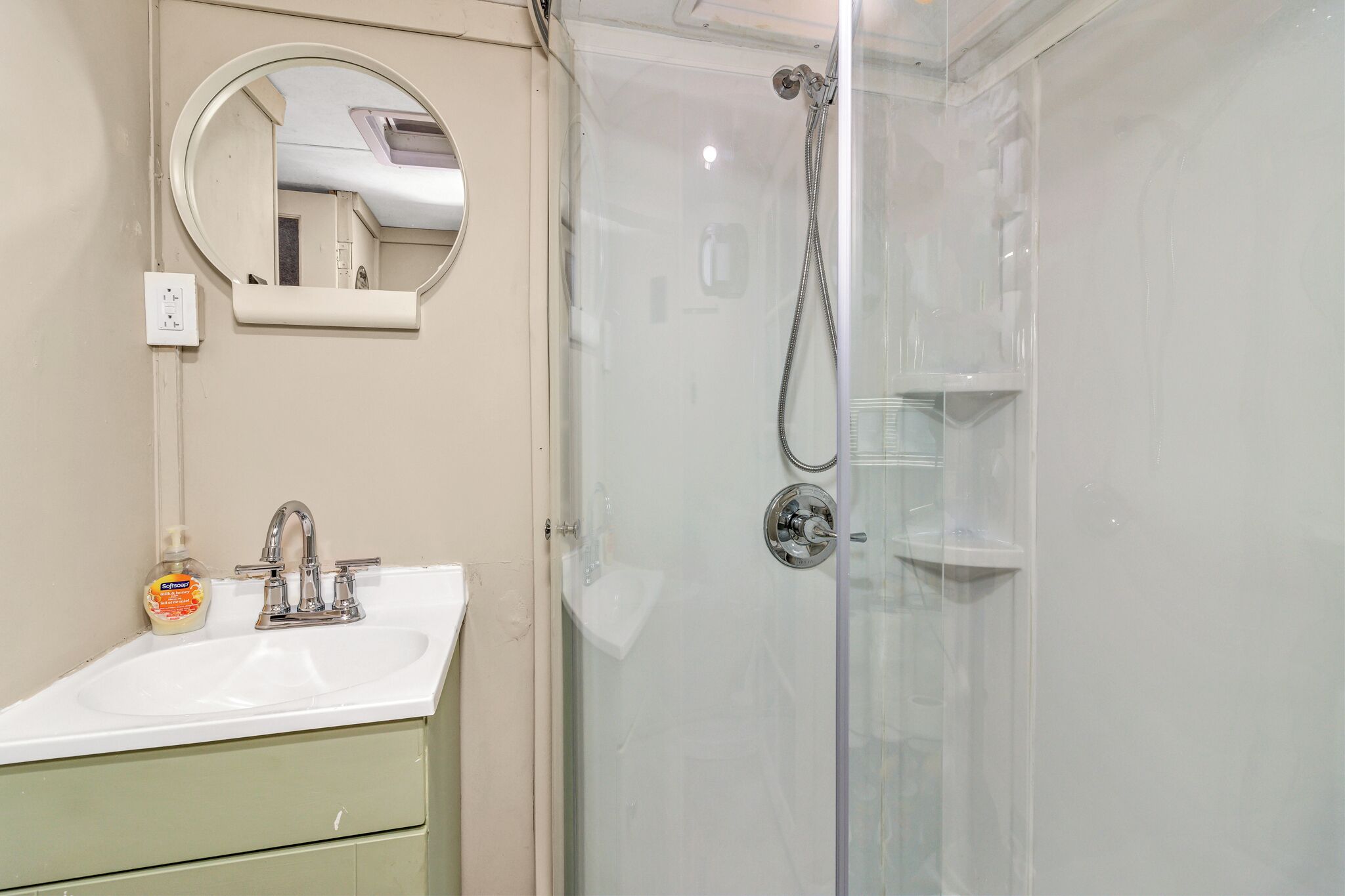 Une salle de bain avec un lavabo, un miroir et une douche fermée par des parois en verre.