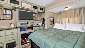 A bedroom with a bed, a fireplace, a television, and a window.