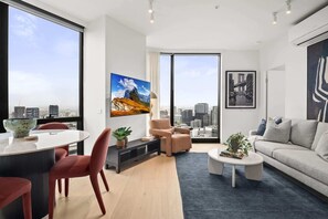 A modern living room with a city view, a dining area, and a sofa. - 1BR Apt |Pool, Gym Near Casino & Southbank Dinning (Southbank)