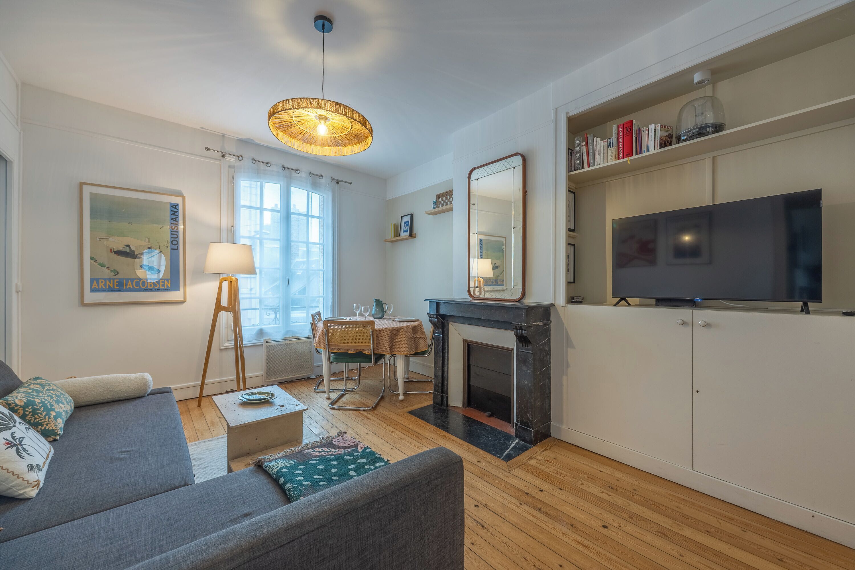 Una sala de estar con sofá, mesa, chimenea, televisor y estantería.