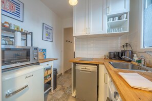 A kitchen with white cabinets, a microwave, a dishwasher, and a sink. - L’ Escapade Trouvillaise - Welkeys (Trouville-sur-Mer)