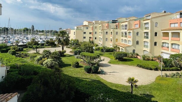 A residential building with multiple balconies, a marina with boats, and well-maintained gardens. - Lovely 2-room with cabin apartment near the port and shops in Cap d'Agde (LE CAP D AGDE)