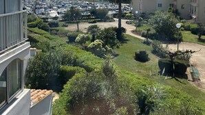 A residential area with a marina, lush greenery, and buildings with balconies. - Lovely 2-room with cabin apartment near the port and shops in Cap d'Agde (LE CAP D AGDE)