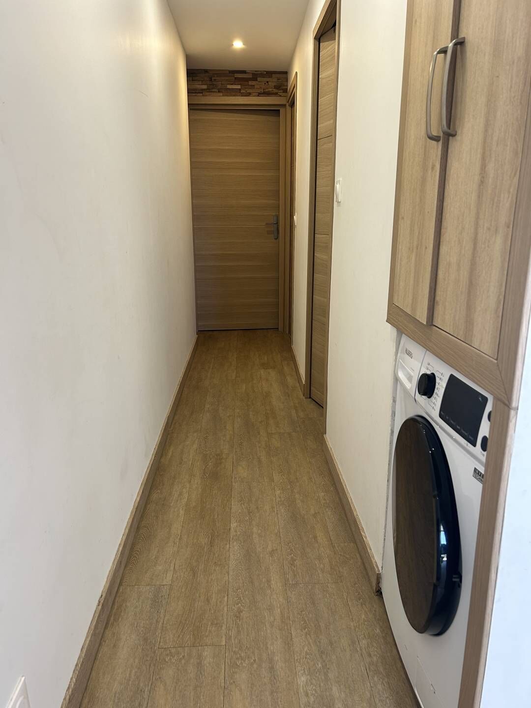 Une buanderie équipée d’un lave-linge, d’un sèche-linge et d’armoires en bois.
