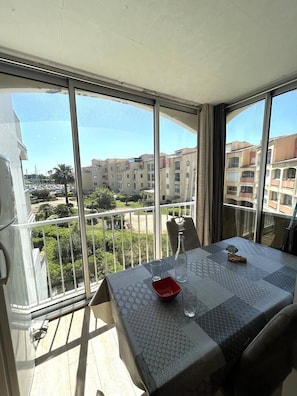 Un balcón con mesa, sillas y vistas a edificios y vegetación.