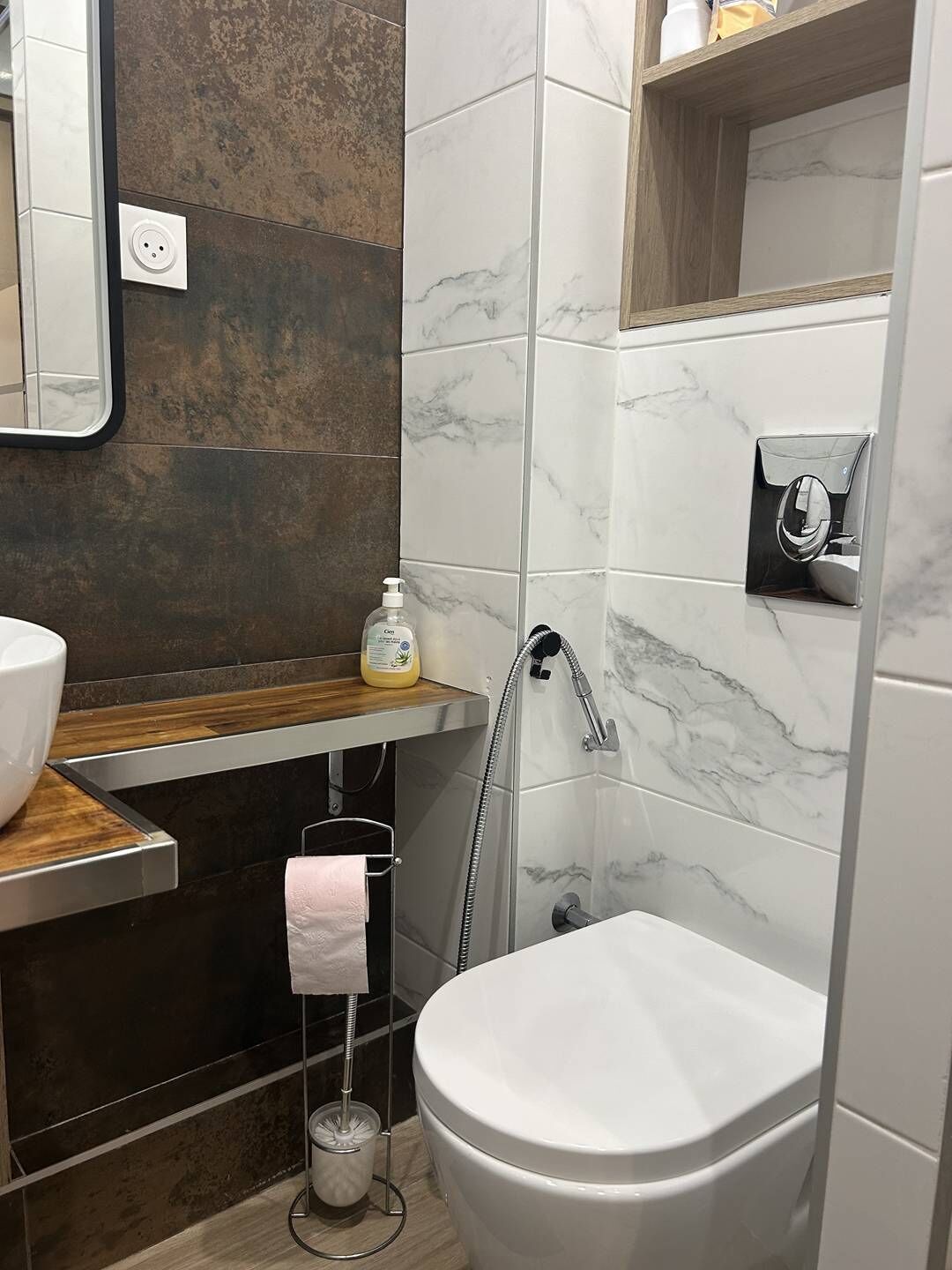 Une salle de bain moderne avec une douche en marbre, des toilettes, un lavabo doté d’un plan de travail en bois et un porte-serviettes.