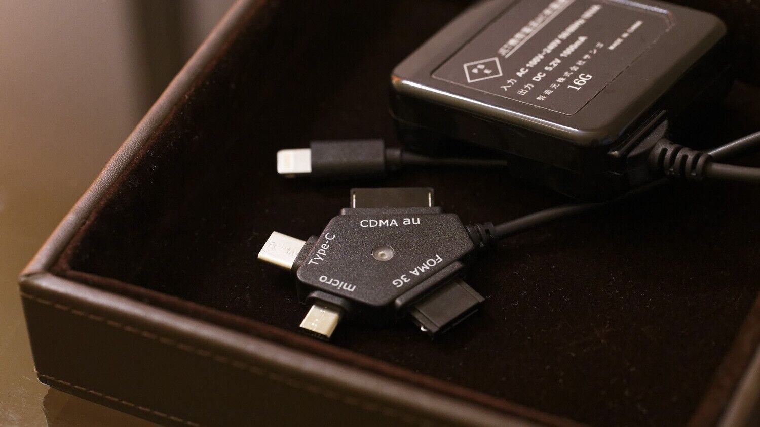 Um cabo USB-C para micro-USB e um adaptador de corrente numa caixa castanha.